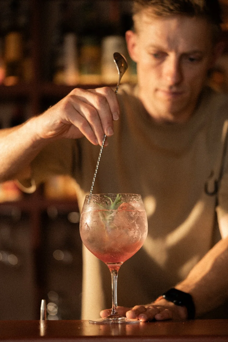 Bartender garnishing a hibiscus rosa sonic cocktail in a balloon glass at Pūblico Mezcaleria Mykonos
