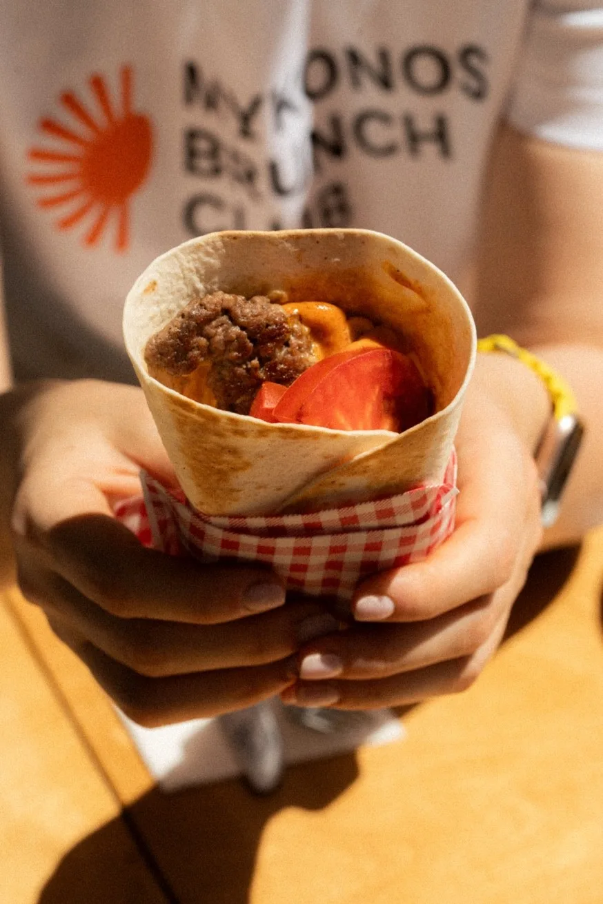 Breakfast burrito held by Mykonos Brunch Club staff — the best brunch spot in Mykonos Town, open daily from 09:00