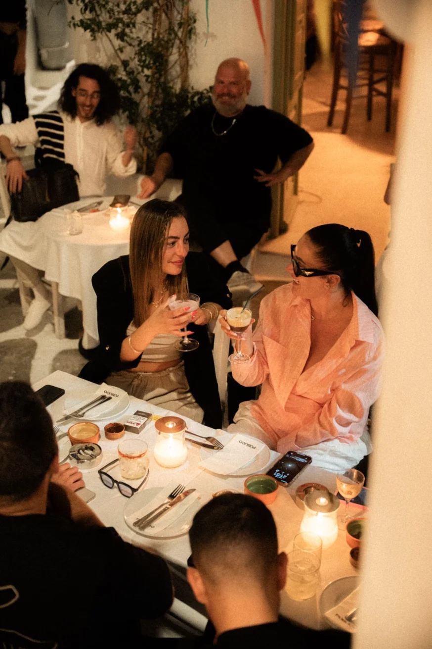 Couple toasting cocktails at a romantic candlelit dinner at Pūblico Mykonos Town — the most romantic restaurant in Mykonos for date night